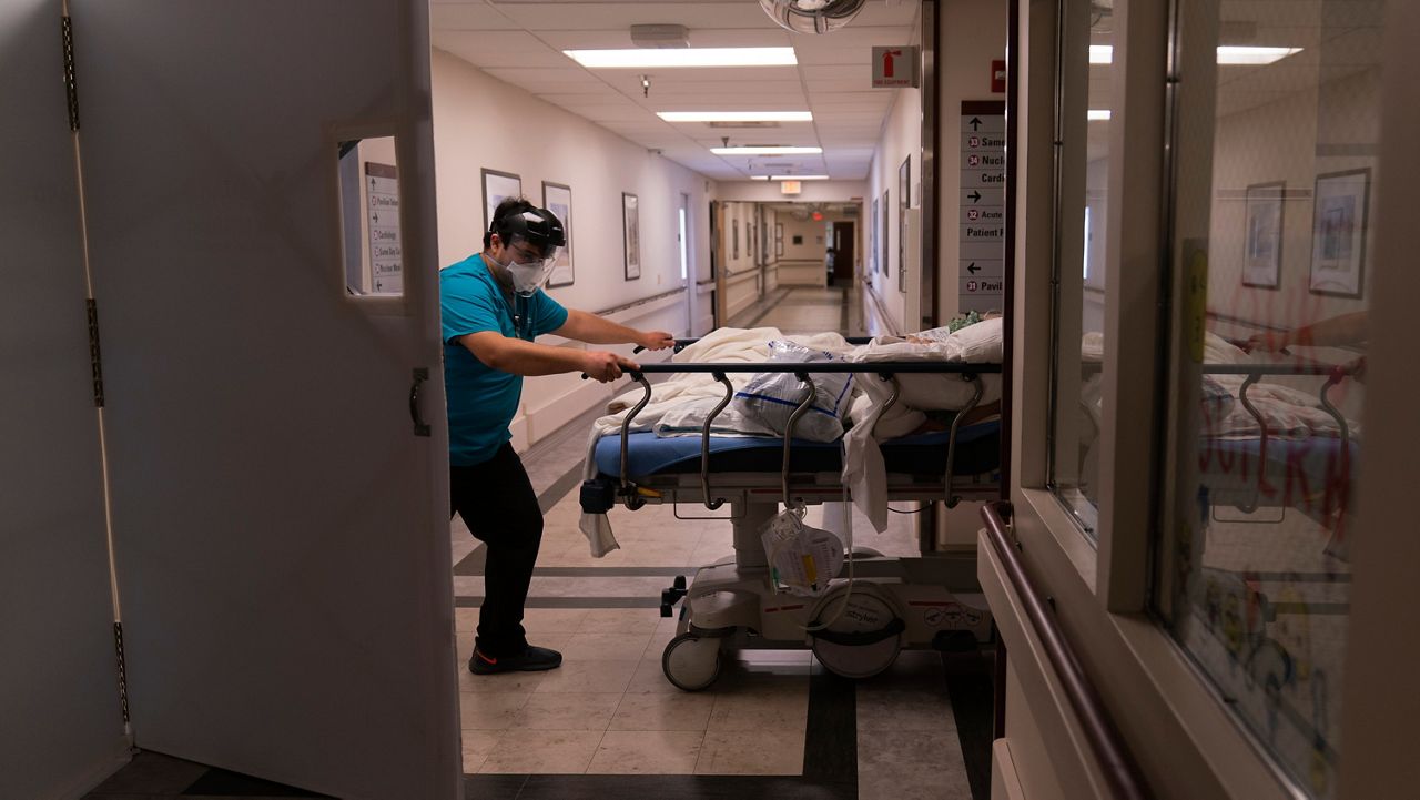 In this Friday, Feb. 19, 2021, file photo, medical transporter Adrian Parrilla moves a patient into a COVID-19 unit at Mission Hospital in Mission Viejo, Calif. There are 3,250 people hospitalized statewide, a drop of more than 85% since peaking around 22,000 in early January, the state Department of Public Health reported Saturday, March 13, 2021. (AP Photo/Jae C. Hong, File)