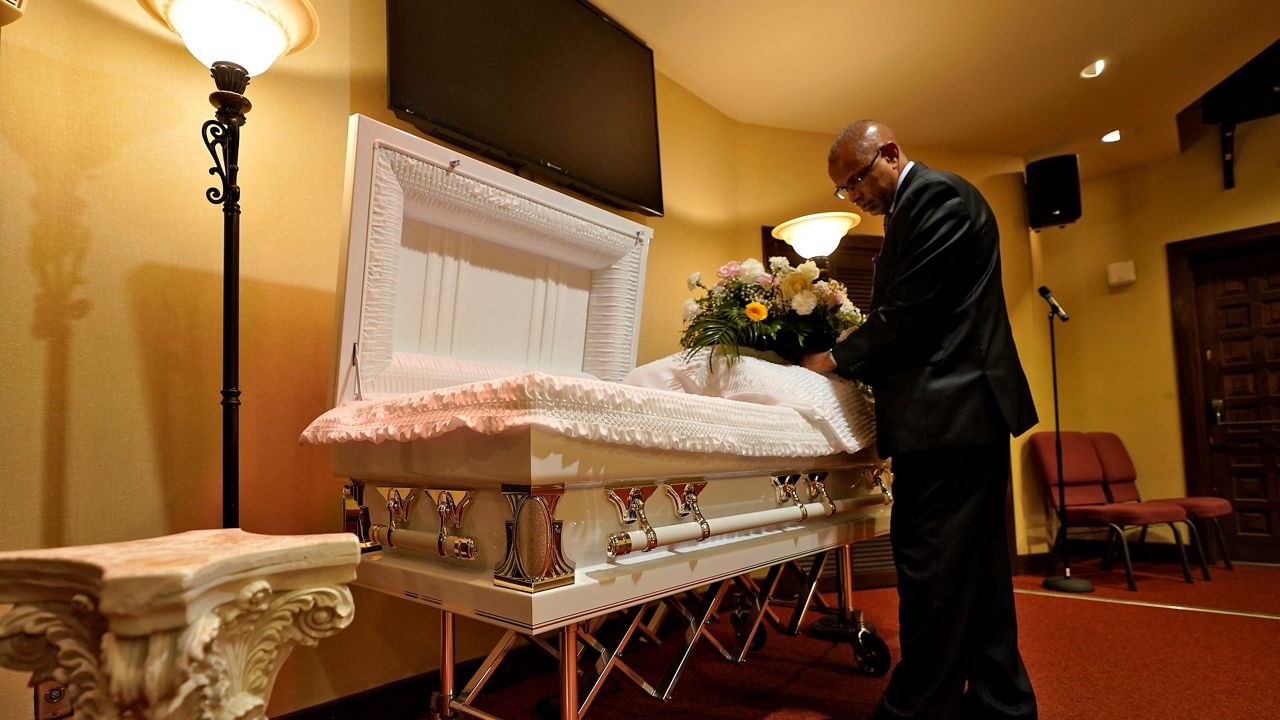 A funeral director arranges flowers on a casket before a service in Tampa, Fla, on Sept. 2. (AP Photo/Chris O'Meara, File)