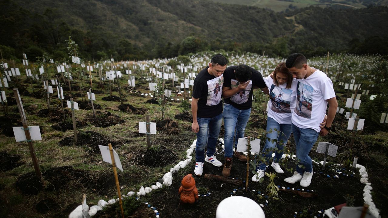 Relatives of Luis Enrique Rodriguez, who died of COVID-19, visit his burial site in Cogua, Colombia, on Oct. 25, 2021. 