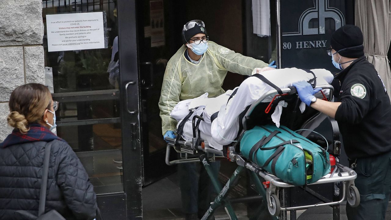 In this April 17, 2020, file photo, a patient is wheeled into Cobble Hill Health Center by emergency medical workers in Brooklyn, New York. (AP Photo/John Minchillo, File) 