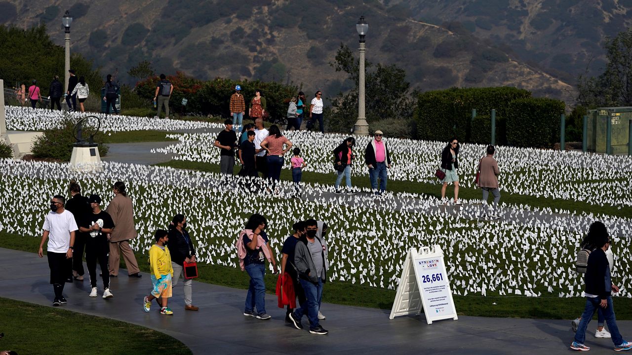 Visitors walk past a memorial for victims of COVID-19 at the Griffith Observatory, Friday, Nov. 19, 2021, in Los Angeles. (AP Photo/Marcio Jose Sanchez)