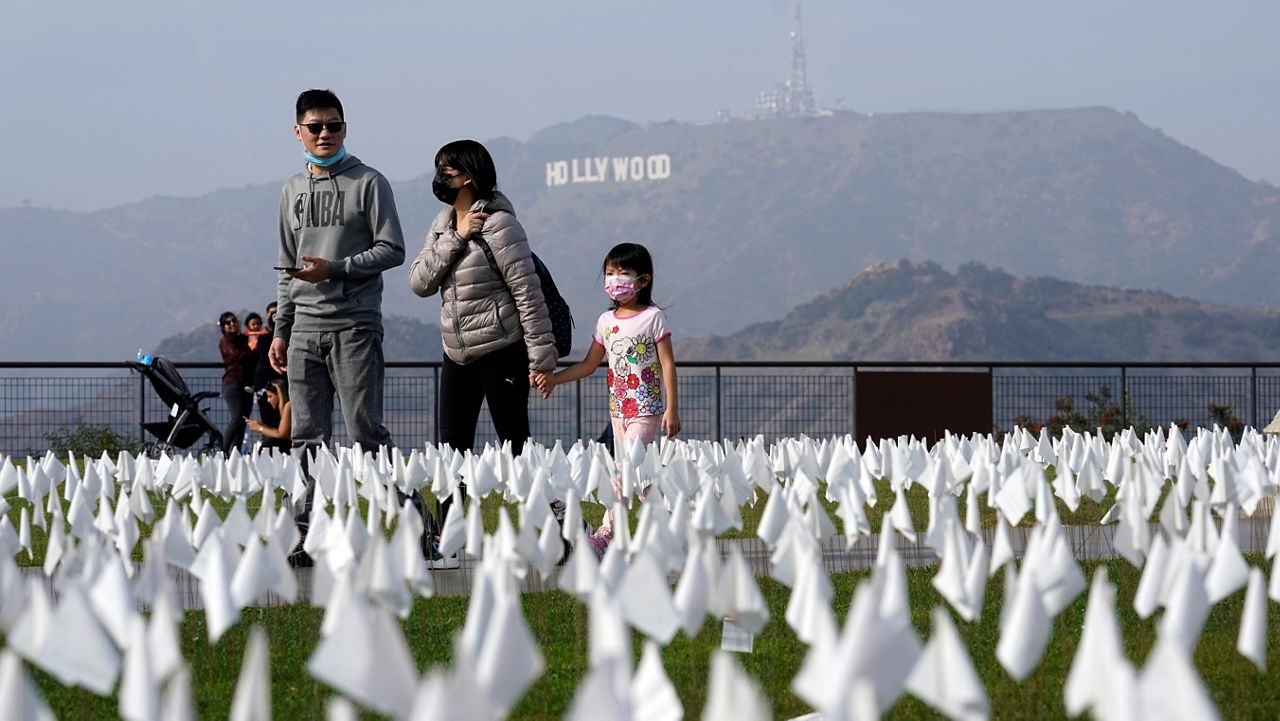 In this Nov. 19, 2021, photo, visitors walk around a memorial for victims of COVID-19 at the Griffith Observatory in Los Angeles. (AP Photo/Marcio Jose Sanchez)