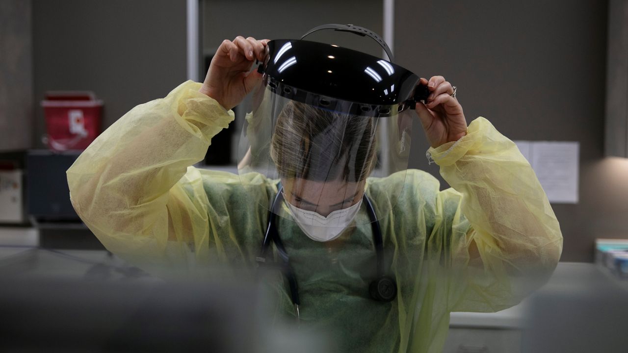 In this June 25, 2020, file photo, a physician assistant takes off her face shield after collecting a nasal swab sample from a patient for COVID-19 testing at Xpress Urgent Care in Tustin, Calif. (AP Photo/Jae C. Hong)