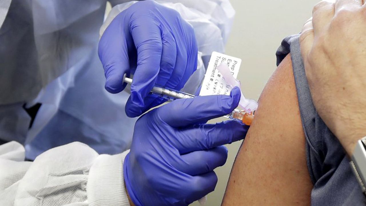 A researcher give a dose of a COVID vaccine to someone. (Associated Press)