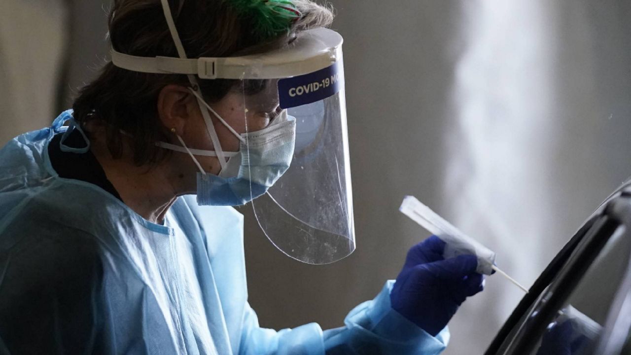 FILE-A healthcare worker transfers a swab to a motorist at mobile testing location for COVID-19, Tuesday, Dec. 8, 2020, in Auburn, Maine. (AP Photo/Robert F. Bukaty, files)