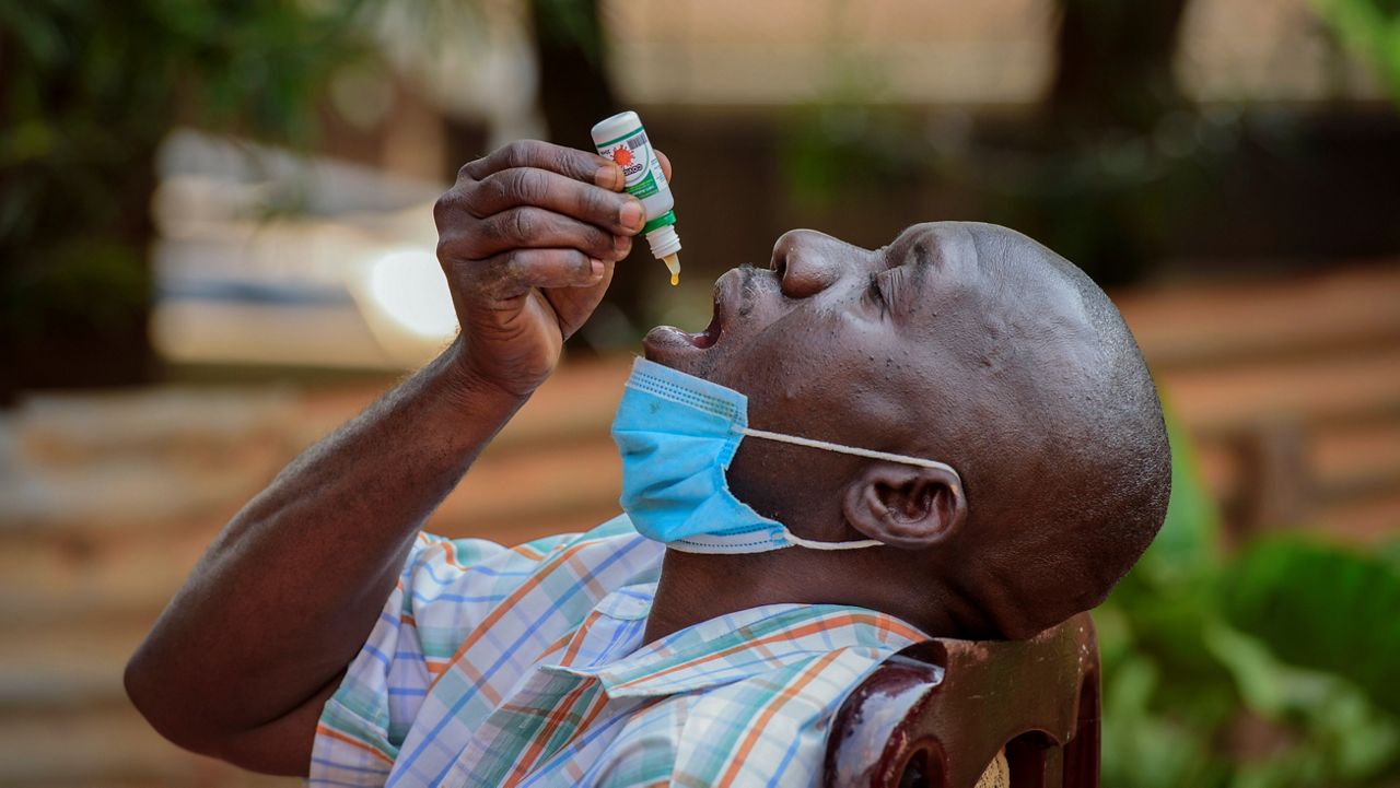 A Uganda man uses "COVIDEX," a locally-made herbal medicine the government approved for use as a supportive treatment for viral infections. (AP/Nicholas Bamulanzeki)