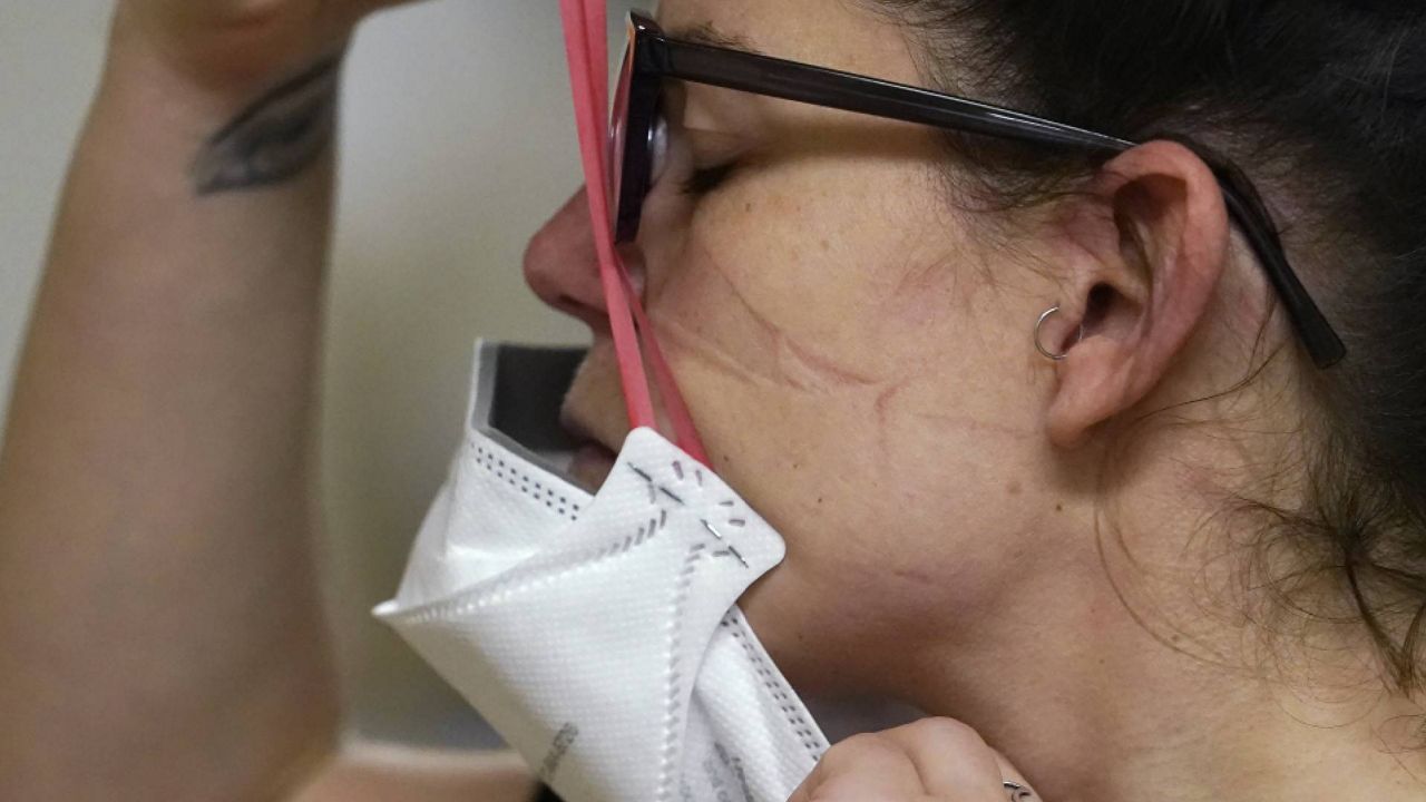 FILE - Registered nurse Jessalynn Dest pulls on a new N95 mask as indentations remain from another she had just removed after leaving a COVID-19 patient room in the acute care unit of Harborview Medical Center, Jan. 14, 2022, in Seattle. (AP Photo/Elaine Thompson, File)