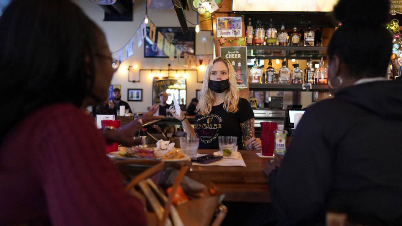 FILE - In this March 10, 2021, file photo, bartender Angie Gibson, center, waits on Monica Ponton, left, and Devona Williams, right, at Mo's Irish Pub in Houston. (AP Photo/David J. Phillip, File)