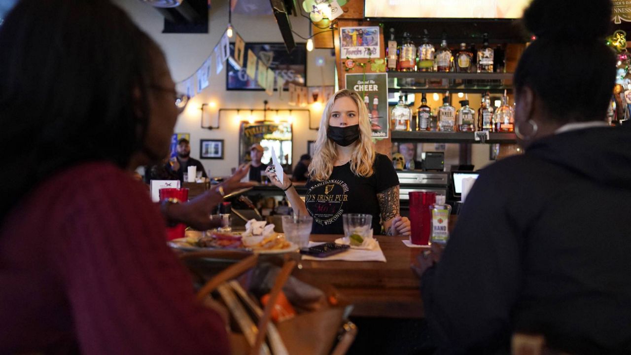 FILE - In this March 10, 2021, file photo, bartender Angie Gibson, center, waits on Monica Ponton, left, and Devona Williams, right, at Mo's Irish Pub in Houston. (AP Photo/David J. Phillip, File)