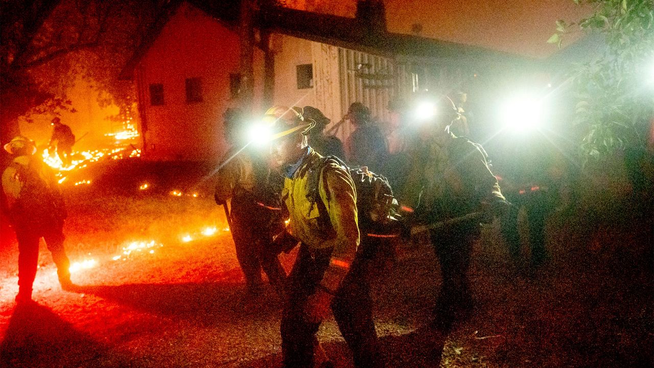 A hand crew works to save a home as the Bear Fire burns through the Berry Creek area of Butte County, Calif., on Wednesday, Sept. 9, 2020. The blaze, part of the lightning-sparked North Complex, expanded at a critical rate of spread as winds buffeted the region. (AP Photo/Noah Berger)