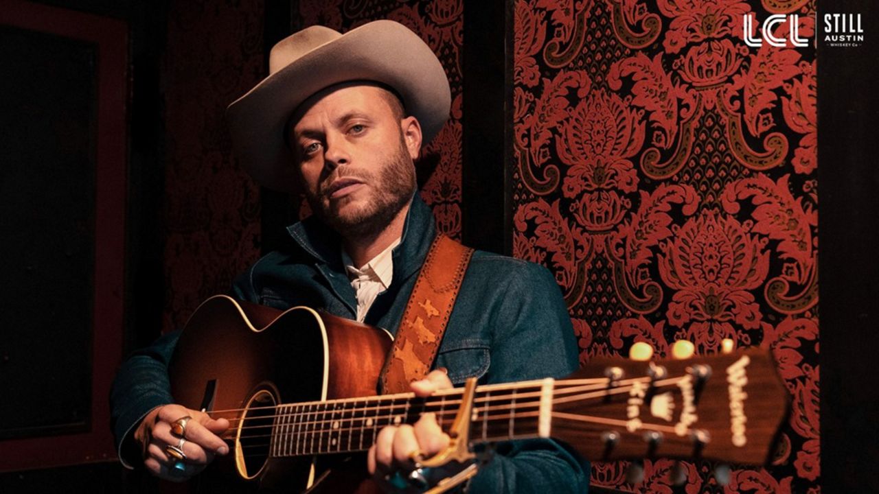 Country artist Charley Crockett strums a guitar. (TexasSports.com)