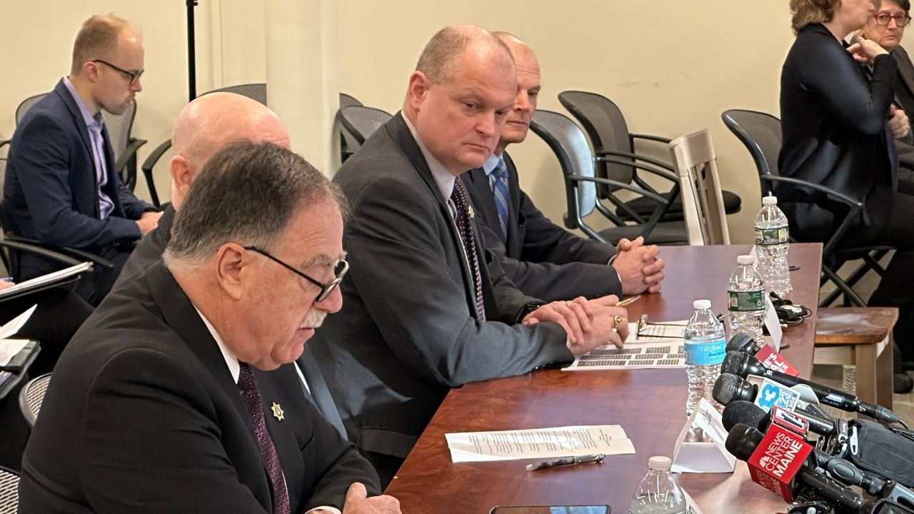 Sagadahoc County Sheriff Joel Merry, left, speaks to the Lewiston shooting commission in January as Sgt. Aaron Skolfield, center, looks on. (Spectrum News file photo)