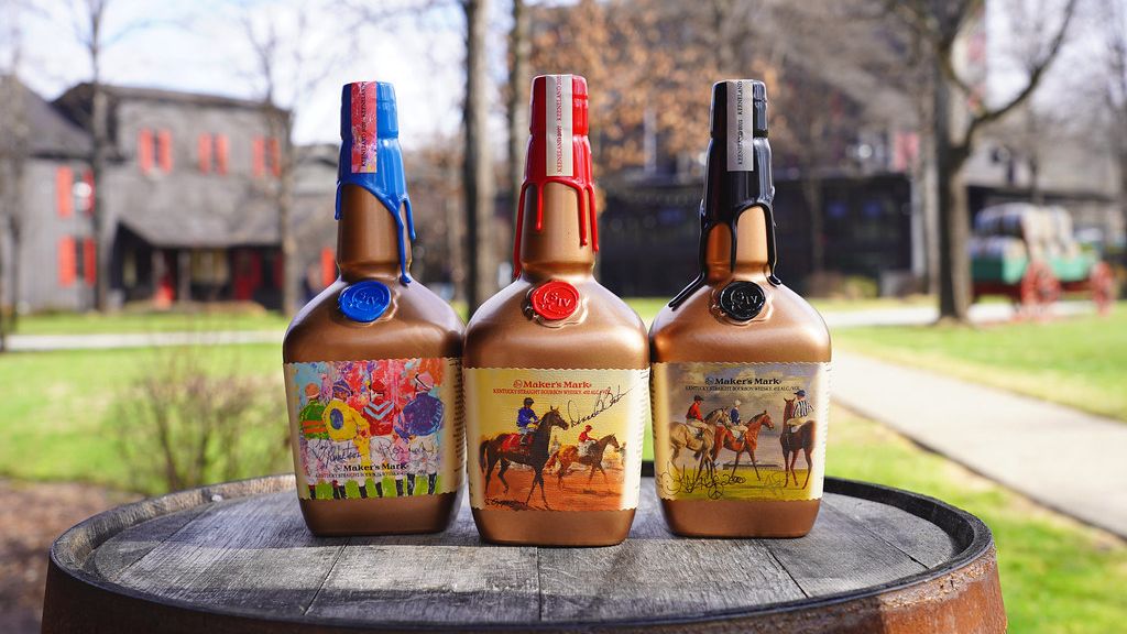 The three Maker's Mark commemorative bottles sit on top of a barrel in a courtyard (Maker's Mark)
