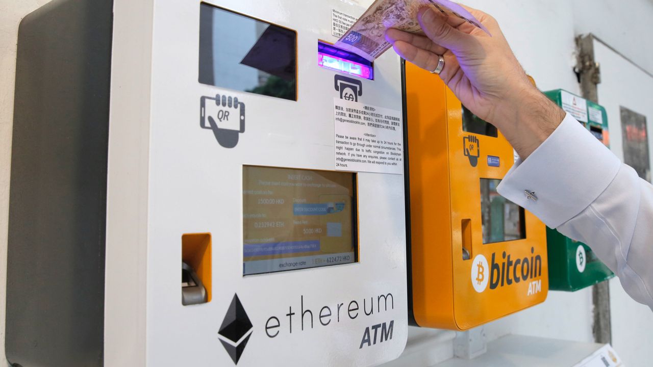 A man uses an ATM for the cryptocurrency Ethereum, next to an ATM for bitcoin, in Hong Kong, May 11, 2018. (AP Photo/Kin Cheung, file)