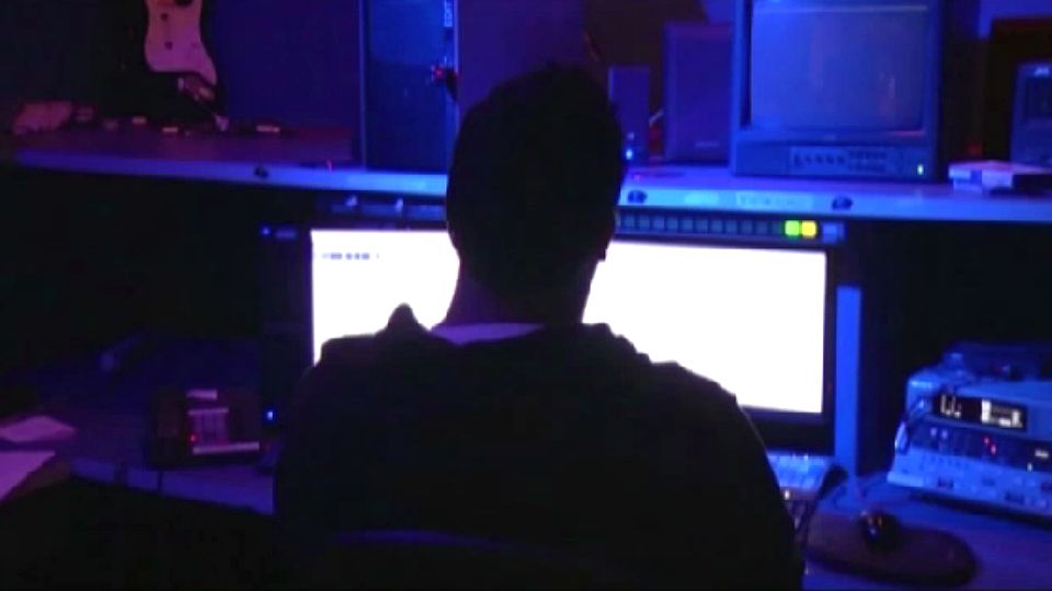 Photo of a person sitting at a desk with a computer (Spectrum News)