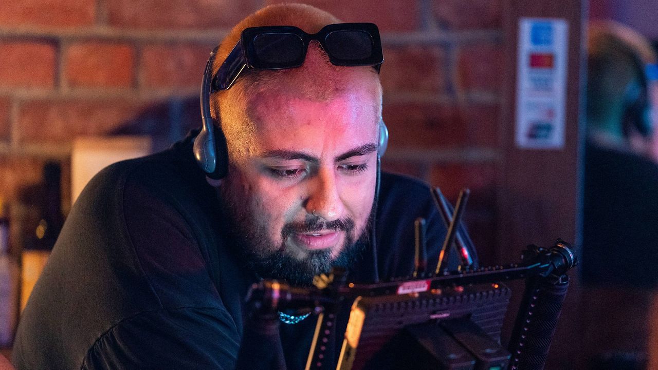 Jorge Xolalpa, a 33-year-old movie director from Mexico checks a shot on a monitor during the filming of his latest movie "Union Station" at "Trunks" gay sports bar in West Hollywood, Calif., on Tuesday, Oct. 4, 2022. (AP Photo/Damian Dovarganes)