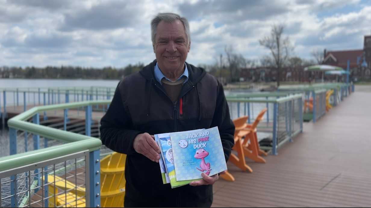 Dale Reich smiles with the books he's written for his grandkids.