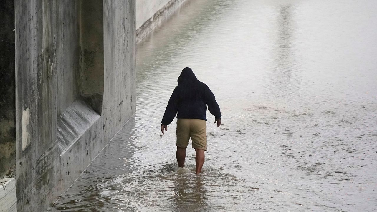 Semi-truck driver Steven Virgil walks into flood waters covering a closed highway to check the depth before trying to drive his truck through in Dallas, Monday, Aug. 22, 2022. Virgil decided to not drive across the water. (AP Photo/LM Otero)