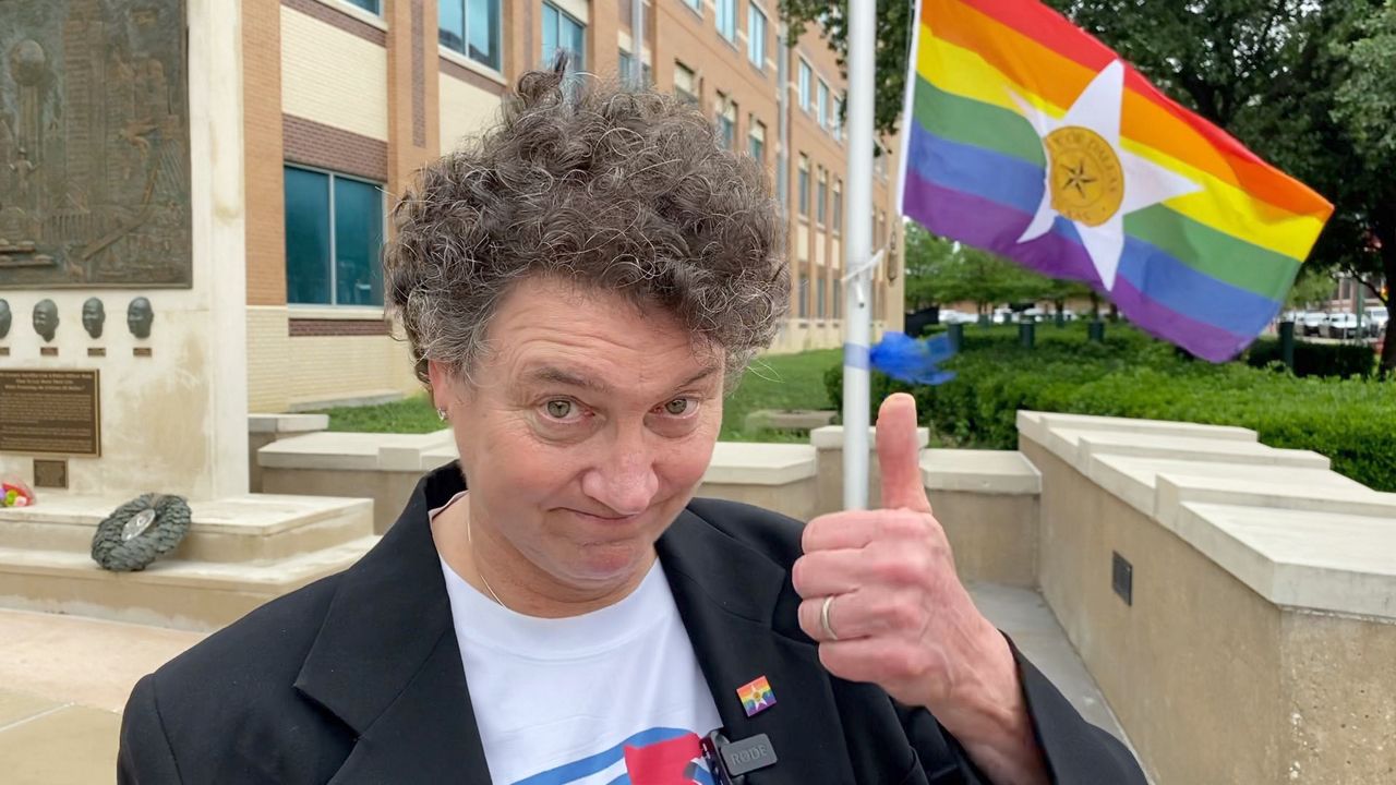 Pictured is Dallas LGBT Task Force member Pam Gerber in front of the Dallas Pride flag before a flag raising ceremony held June 1 at Dallas Police Department headquarters. (Spectrum News 1/Lupe Zapata)