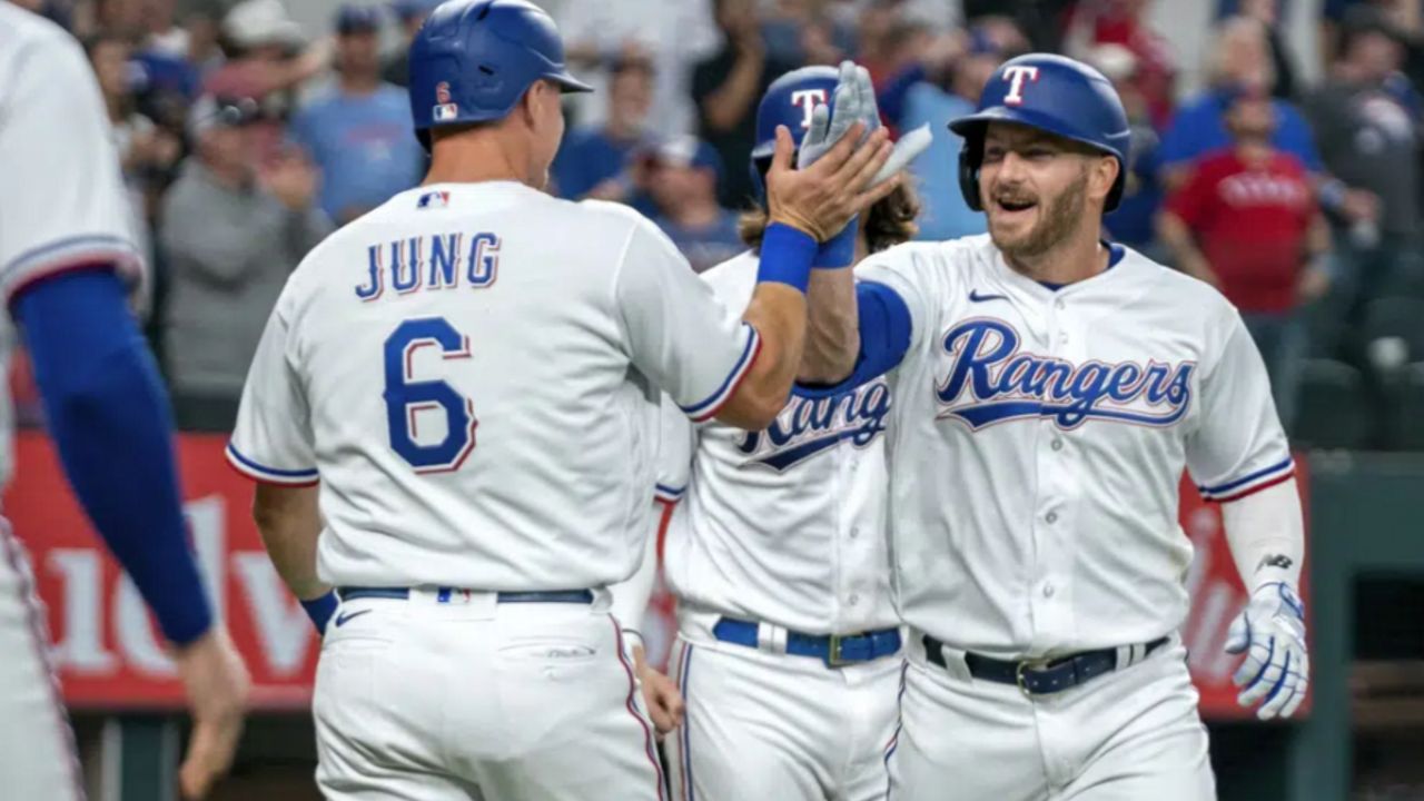 Texas Rangers' Robbie Grossman, right, is congratulated by Josh Jung after hitting a three-run home run that scored Jung and Jonah Heim, center, during the fourth inning of an opening day baseball game against the Philadelphia Phillies, Thursday, March 30, 2023, in Arlington, Texas. (AP Photo/Jeffrey McWhorter)