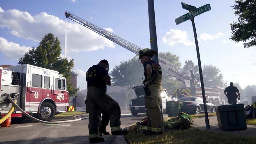 Firefighters from multiple departments work on putting out hot spots when a nearby grass fire burned several homes in Balch Springs, Texas, Monday, July 25, 2022. (AP Photo/Tony Gutierrez)