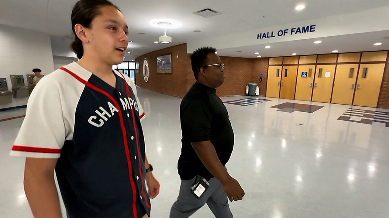 Senior Danny San walks the halls of Armwood High School with his band teacher, Alex Pedigo. (Spectrum News)