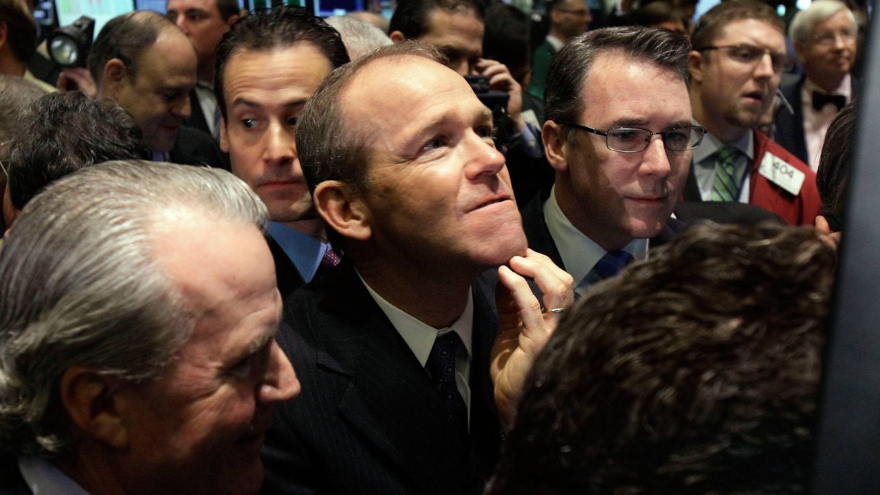 Then-Nielsen Company CEO David Calhoun, center, watches progress as he waits for the company's IPO to begin trading, Jan. 26, 2011, on the floor of the New York Stock Exchange. (AP Photo/Richard Drew, File)