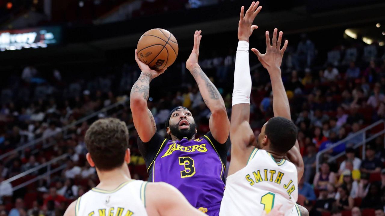 Los Angeles Lakers forward Anthony Davis (3) shoots between Houston Rockets center Alperen Sengun, left, and forward Jabari Smith Jr., right, during the first half of an NBA basketball game Sunday in Houston. (AP Photo/Michael Wyke)