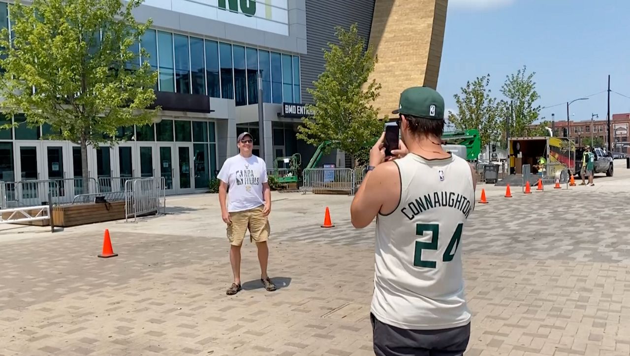 Two Milwaukee Bucks Fans take pictures outside Fiserv Forum Wednesday, the day after the team won the NBA Finals 