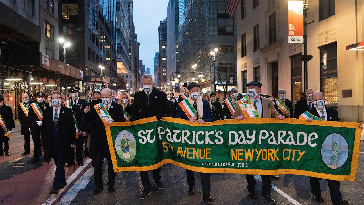 Mayor Bill de Blasio, center, marches during the St. Patrick's Day Parade early Wednesday, March 17, 2021 in New York. The city's usual huge parade with marching bands has been canceled due to COVID-19, but a few dozen people marched at 6 a.m. to keep the tradition alive, a spokesperson for de Blasio said. (AP Photo/Mark Lennihan)