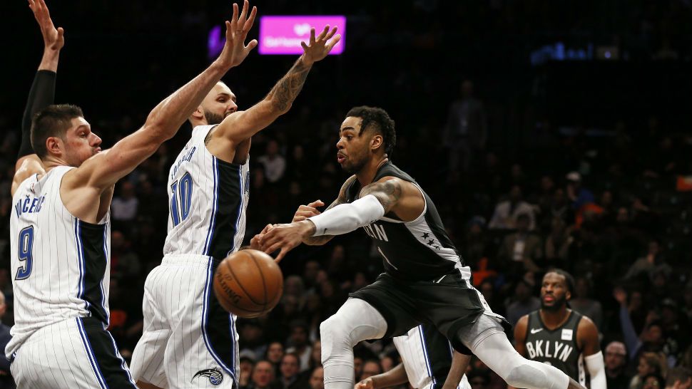 Brooklyn Nets guard D'Angelo Russell (1) passes around Orlando Magic guard Evan Fournier (10) and Magic center Nikola Vucevic (9) during the second half of an NBA basketball game Wednesday, Jan. 23, 2019, in New York. The Nets defeated the Magic 114-110. (AP Photo/Adam Hunger)