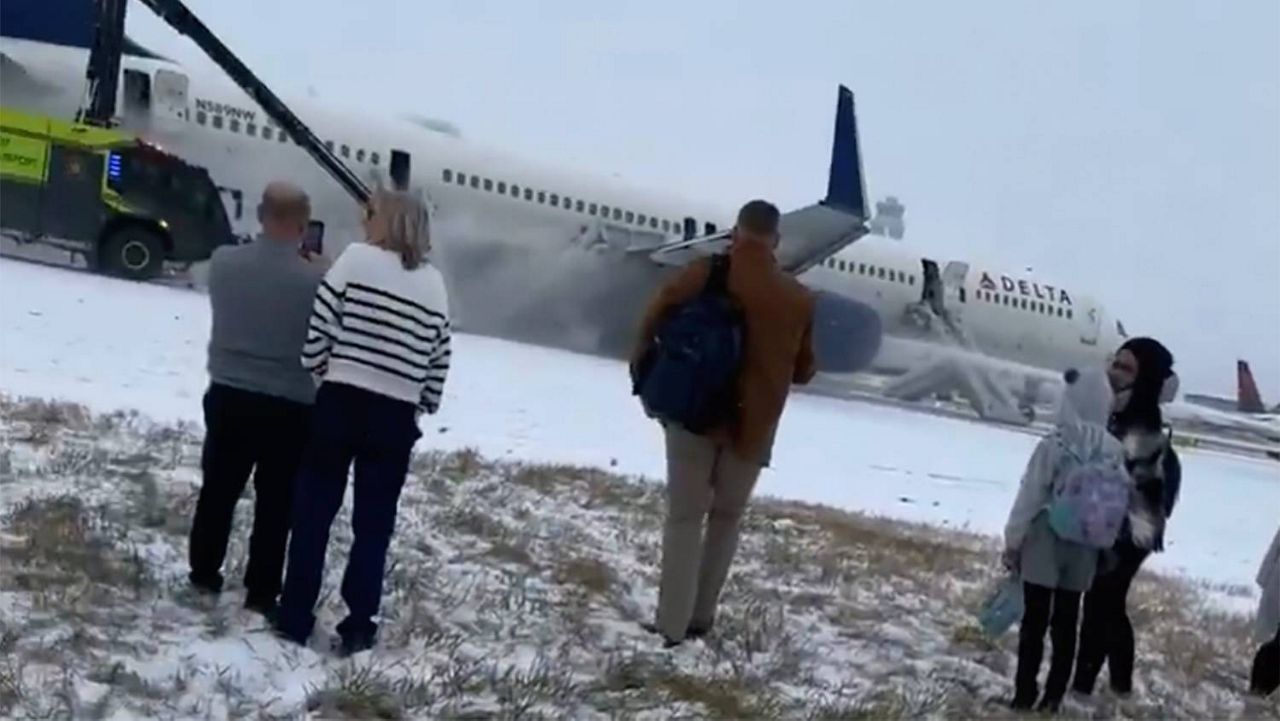 This image provided by Tyrel Mollerud shows passengers waiting on the runway after evacuating from the Delta flight at the Hartsfield-Jackson Atlanta International Airport on Friday, Jan. 10, 2025. (Tyrel Mollerud via AP)