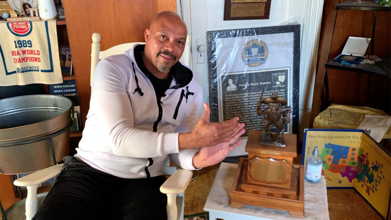 Former pro basketball player and college standout Fennis Dembo poses with memorabilia from his playing days. (Spectrum News 1/Adam Rossow)
