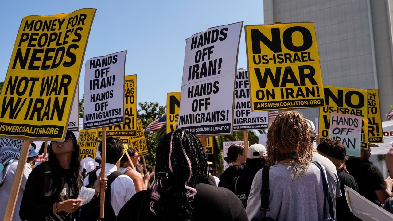 Anti-war demonstrators hold signs outside the Wilshire Federal Building in Los Angeles on Sunday, following U.S. airstrikes on Iran's nuclear facilities. (AP Photo/Jae C. Hong)