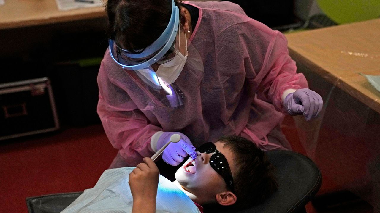 Clayton Warner holds a mirror as dental hygienist Mary Davis examines his teeth at the Christa McAuliffe School in Concord, N.H., Wednesday, Feb. 21, 2024. (AP Photo/Robert F. Bukaty)