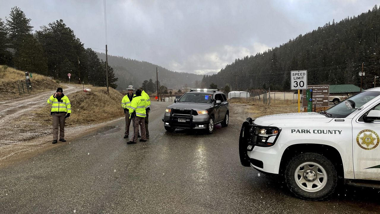 Sheriff deputies block a road Wednesday in the town of Bailey, Colo., where authorities found an abandoned car that belonged to the suspect in a shooting of two administrators at a Denver high school. (AP Photo/Thomas Peipert)