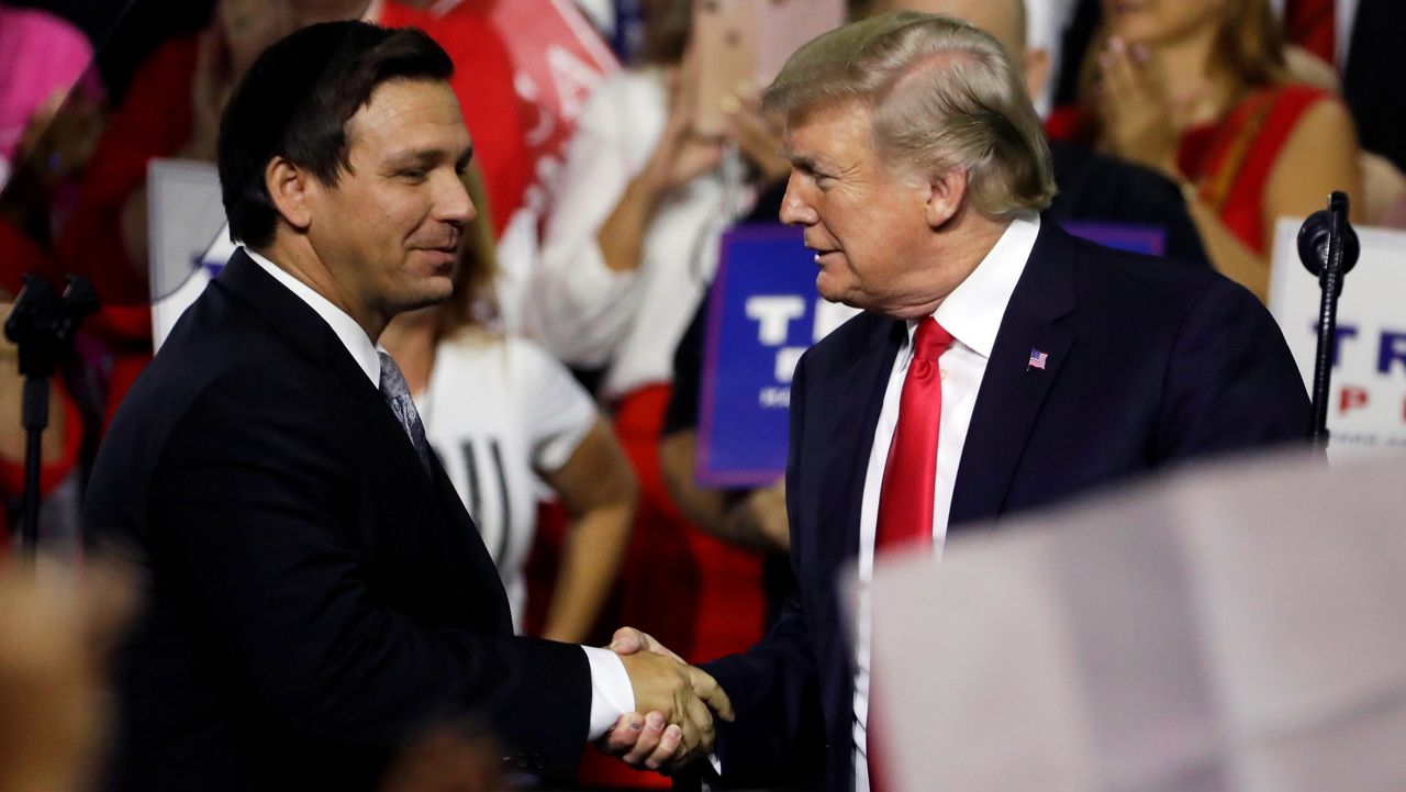 FILE - In this July 31, 2018, file photo, President Donald Trump, right, shakes hands with Florida Republican gubernatorial candidate Ron DeSantis during a rally in Tampa, Fla. (AP Photo/Chris O'Meara, File)