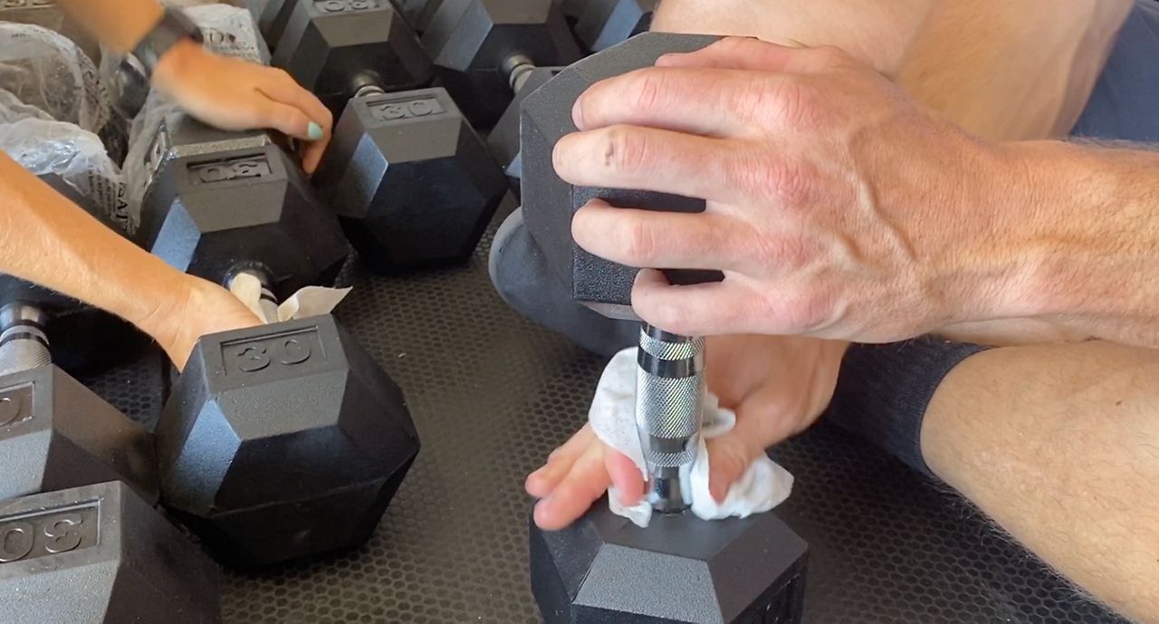 Man wipes down dumbbell at a gym amid the coronavirus pandemic (file photo)
