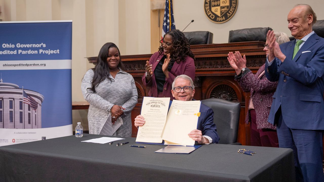 Gov. Mike DeWine displays pardon signed today for Stacey Howard, pictured far left. (Gov. Mike DeWine's office)