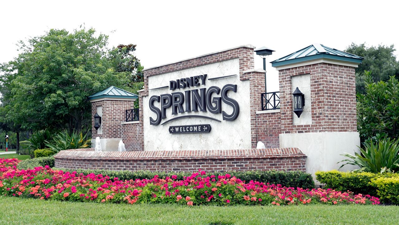 FILE - A sign near one of the entrances to Disney Springs is seen May 18, 2020, in Lake Buena Vista, Fla. The husband of a New York doctor who died shortly after dining at a Disney Springs restaurant last year accused Walt Disney Parks and Resorts of negligence in a 19-page lawsuit filed in Florida. (AP Photo/John Raoux, file)