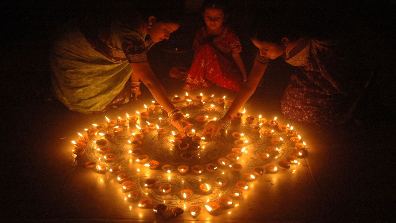 Women light earthen lamps on the eve of the Hindu festival of Diwali in India.