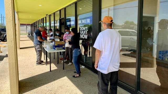 Volunteers with the R3 Student Outreach Food Pantry hand out food to people waiting in line. (Courtesy: Juan Ramos / R3 Student Outreach Food Pantry)