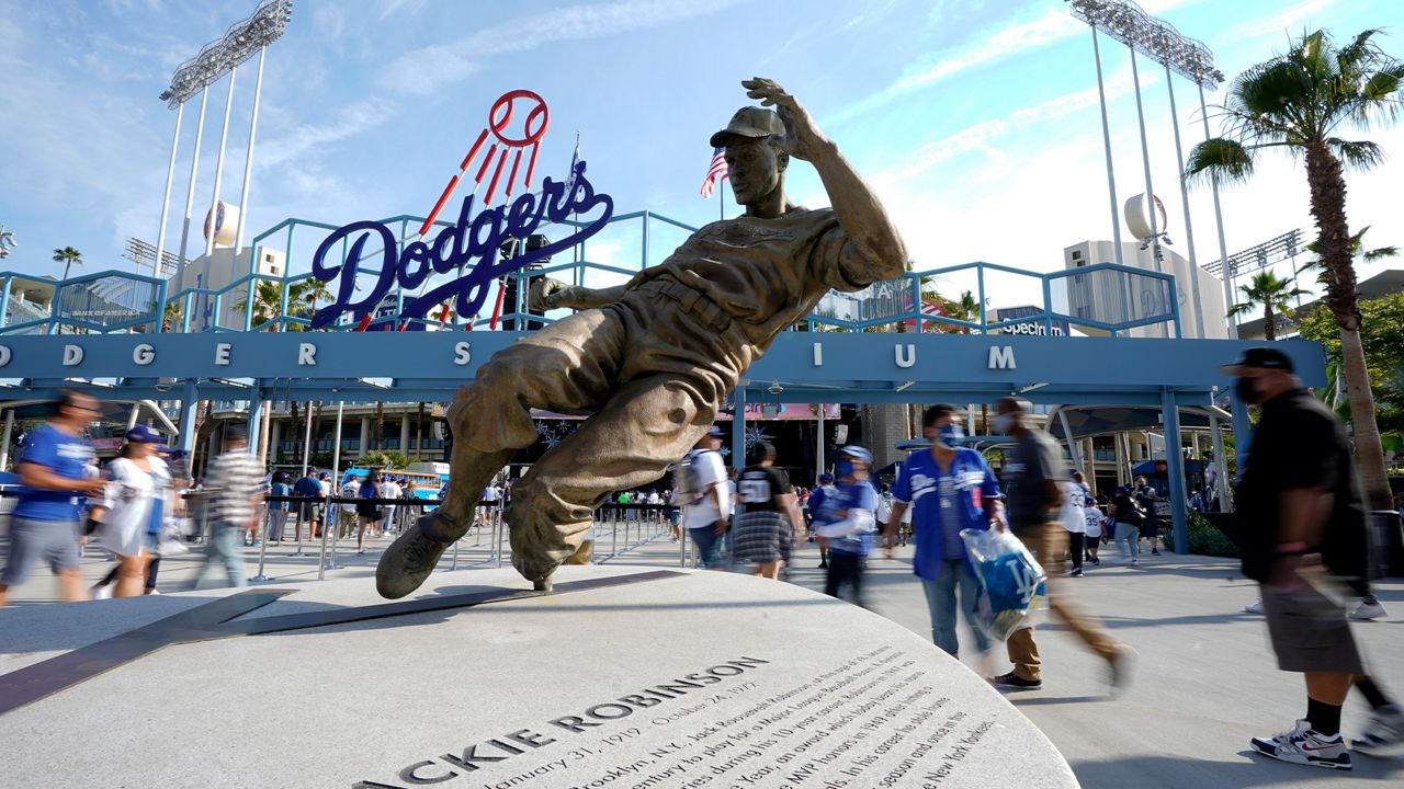 Fans walk by a statue of Jackie Robinson as they enter Dodger Stadium prior to a baseball game between the Dodgers and the Philadelphia Phillies Tuesday, June 15, 2021, in Los Angeles. (AP Photo/Mark J. Terrill)