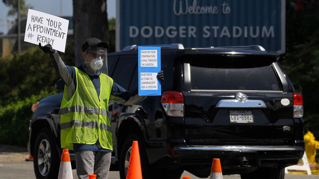 Workers direct cars as they wait in line for coronavirus testing at Dodger Stadium Tuesday, July 14, 2020, in Los Angeles. (AP Photo/Mark J. Terrill)