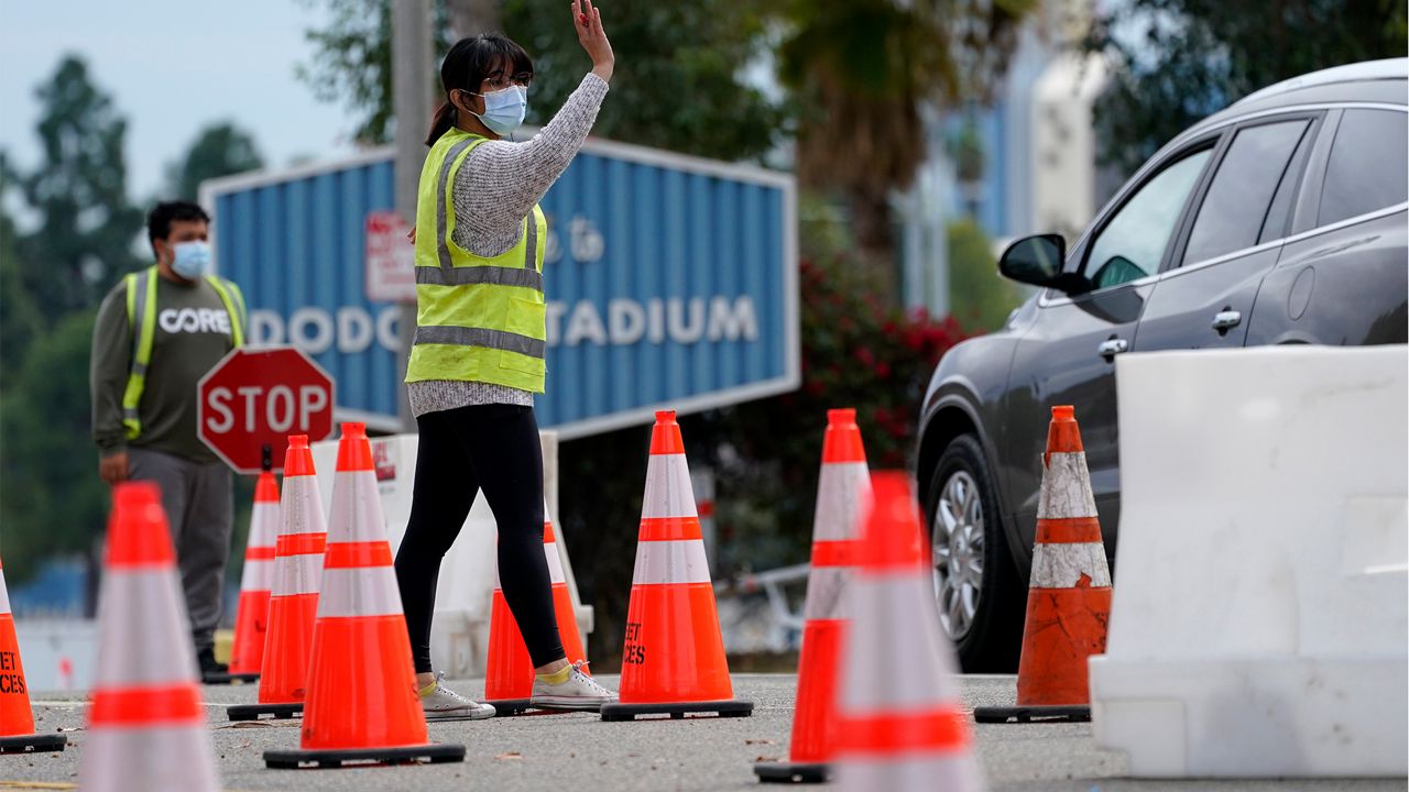 Cars are waved in as people arrive at the Dodger Stadium parking lot to receive the COVID-19 vaccine Monday, Feb. 1, 2021, in Los Angeles. (AP Photo/Mark J. Terrill)