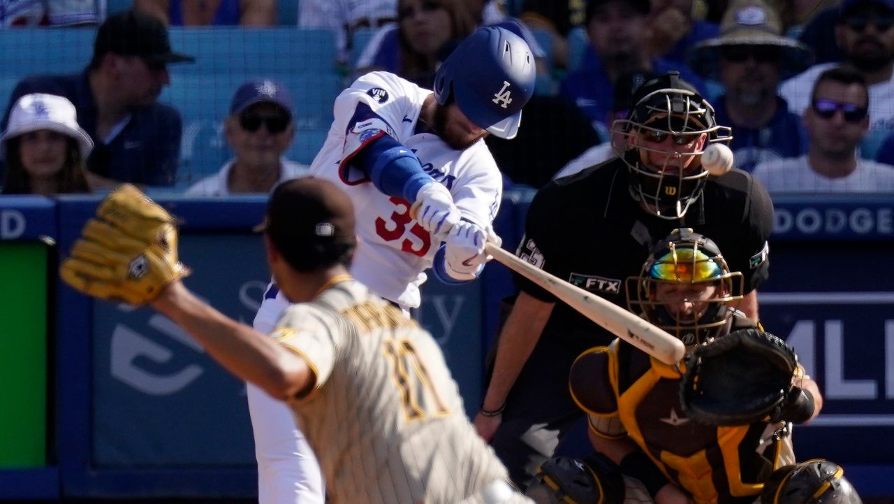 Los Angeles Dodgers' Cody Bellinger, second from left, hits a solo home run as San Diego Padres starting pitcher Yu Darvish, left, watches along with catcher Austin Nola, right, and home plate umpire Lance Barksdale during the third inning of a baseball game Sunday, Aug. 7, 2022, in Los Angeles. (AP Photo/Mark J. Terrill)