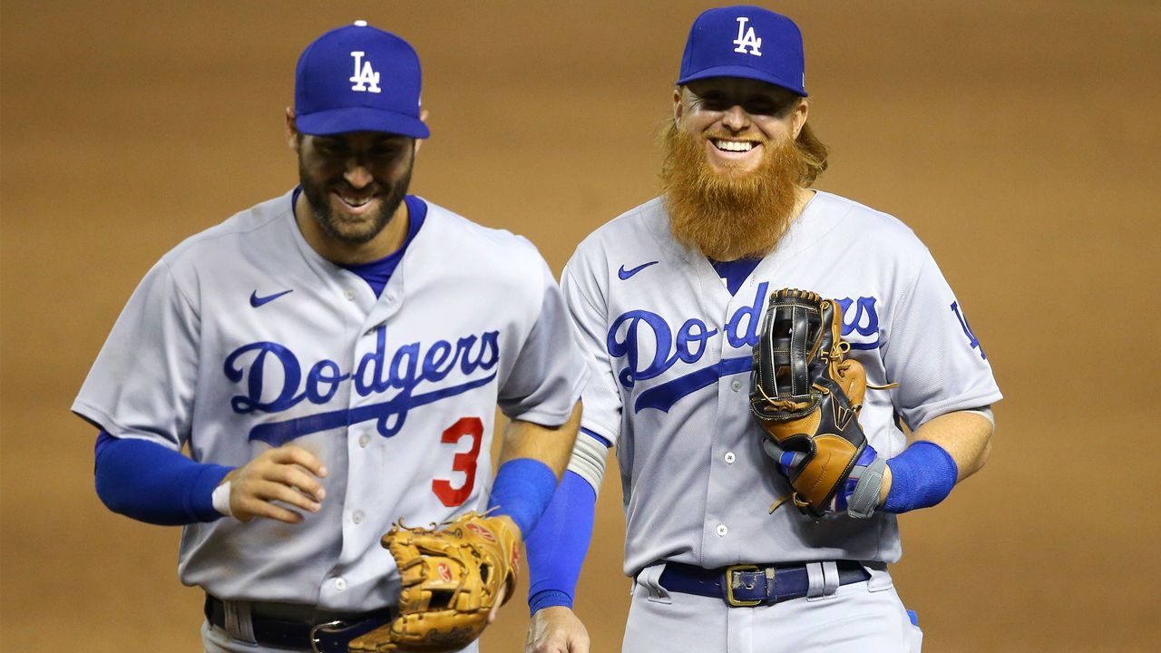 Los Angeles Dodgers' Chris Taylor (3) and Justin Turner, right, smile as they jog off the field after the third out against the Arizona Diamondbacks during the fifth inning of the Diamondbacks' home-opener baseball game Thursday, July 30, 2020, in Phoenix. (AP Photo/Ross D. Franklin)