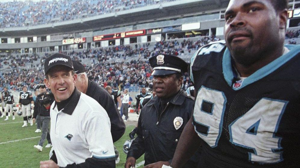 FILE - Carolina Panthers coach Dom Capers smiles as he leaves the field with Sean Gilbert (94) after the Panthers' 20-13 win over the St. Louis Rams in an NFL football game in Charlotte, N.C., Dec. 20, 1998. The Panthers announced that Capers, who was coach from 1995-98, has been added to new coach Frank Reich’s staff as a senior defensive assistant. Capers coached Reich in 1995 when the Panthers broke into the league as an expansion team. (AP Photo/Chuck Burton, File)