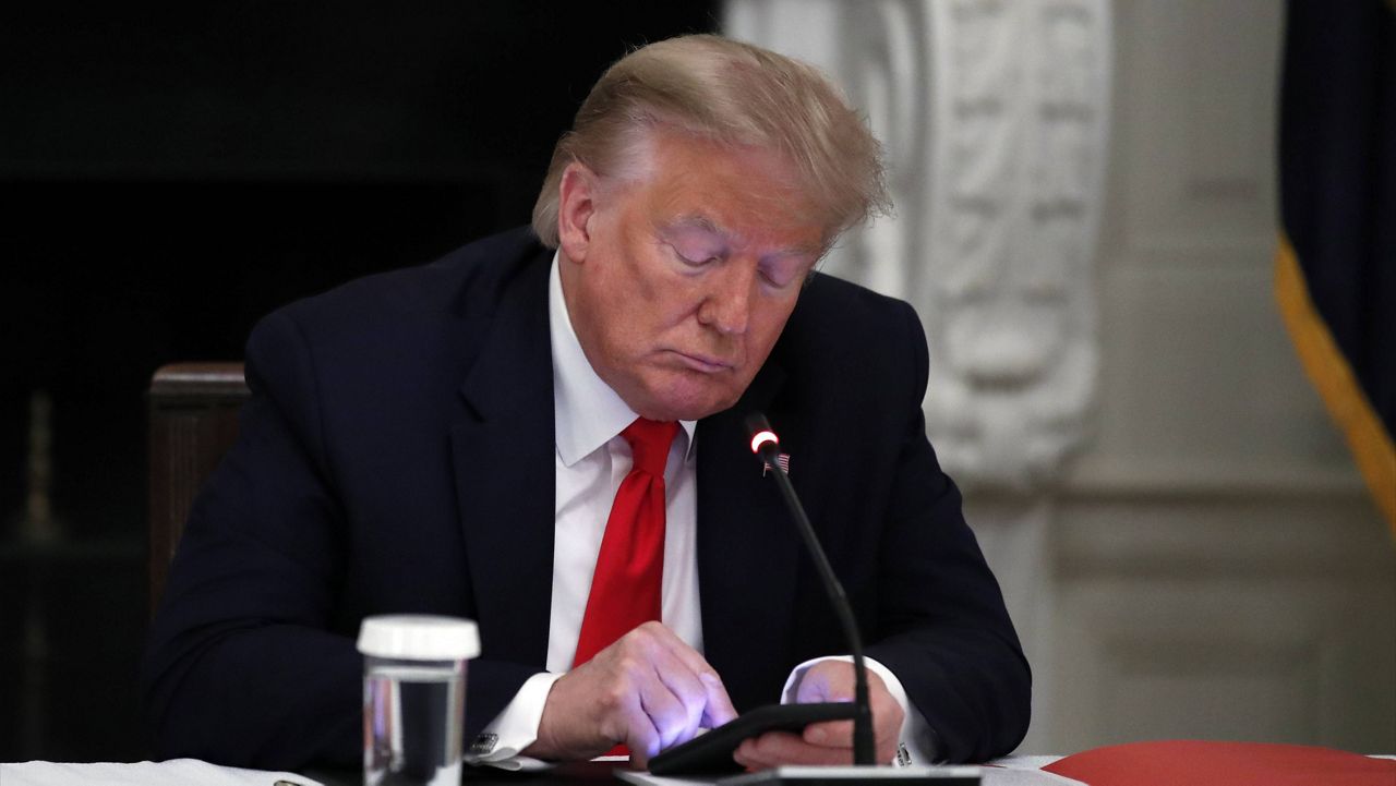 In this June 18, 2020, file photo, President Donald Trump looks at his phone during a White House roundtable with governors. (AP Photo/Alex Brandon, File)