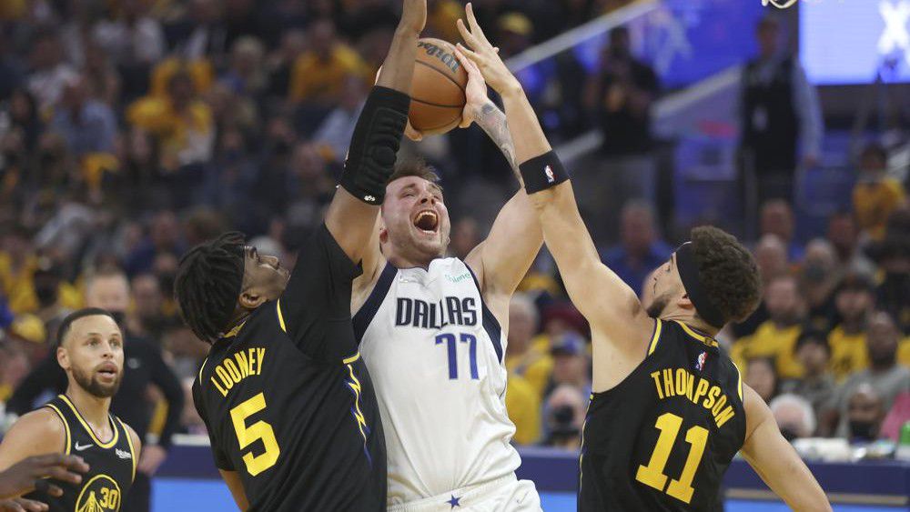Dallas Mavericks guard Luka Doncic (77) shoots between Golden State Warriors center Kevon Looney (5) and guard Klay Thompson (11) during the first half of Game 1 of the NBA basketball playoffs Western Conference finals in San Francisco, Wednesday, May 18, 2022. (AP Photo/Jed Jacobsohn)